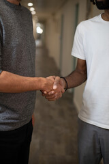 gros plan sur les mains de deux collègues d'origines différentes qui se disent bonjour ou concluent un accord en se serrant les mains. Une main blanche et une main noire. Symbole de diversité. © Tof - Photographie