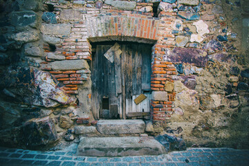 Facade Of An Abandoned House With An Old Patched Wooden Door. Abandoned Houses. Image With Texture And Copy Space. Evicted Housing Concept