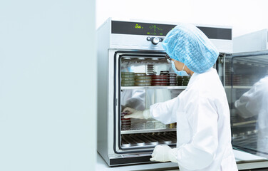 Unidentified microbiologist is place the petri dish and tubes into incubator to incubate the...