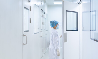 Unidentified microbiologist is open the cleanroom door to enter the room in clean area of microbial...