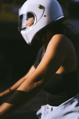 A young woman in a motorcycle full face helmet  rides a motobike. Surfer on a motorcycle, surfboard in racks. Safe driving in Asia.