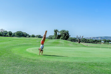 Handstand pirouette executed by a girl next to hole 12 of a golf course