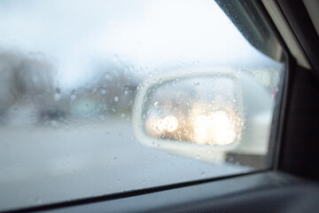 Blurry car silhouette seen through snowy and wet windscreen