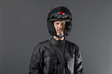 Studio shot of Motorcyclist biker in black equipment looking at camera.