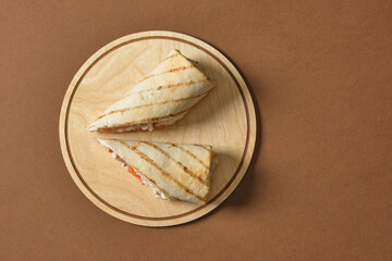 cut roll with chicken on a tray on a brown background, copy space, stuffing in pita bread, fast food concept