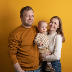 mom, dad and boy on a yellow background. A family with a baby in their arms.