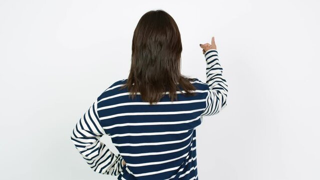 Young brunette woman pointing back with the index finger over isolated background