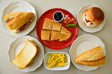 Top view of table scene with assorted take out or delivery foods. Meat and chicken doner kebab sandwich, wrap and on the plate with vegetables and sauce, including fries and pickles.