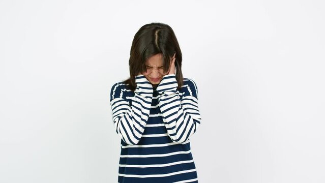 Young brunette woman covering both ears with hands. Frustrated expression  over isolated background
