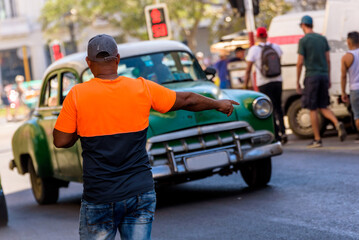 Cuban man raising hand calling a collective taxi in Old Havana. Young Afro Cuban man hailing a traditional shared taxi on the street.
