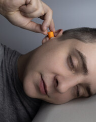 The man puts on earplugs. Close-up of an orange noise barrier. Deep sleep. The ENT doctor advises...