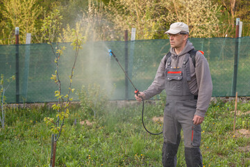 The man works in the spring garden and sprayes with the help of rechargeable chemicals for sprayers...