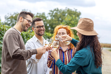 Group of four friend in vineyard talk and smile with glasses full of vine in hands