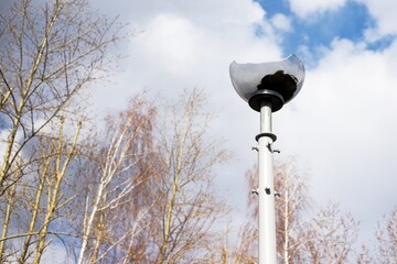 old broken street lamp on a high leg with a broken shade to scatter light