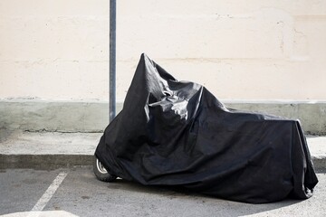 a rare motorcycle is hidden from prying eyes by a black cover next to a disabled sign in the...