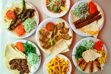 Delicious meat kebab with fresh vegetable salad served with variety of Turkish dishes and appetizers. Top view of assorted Turkish food and meze, tasty and healthy Mediterranean cuisine.