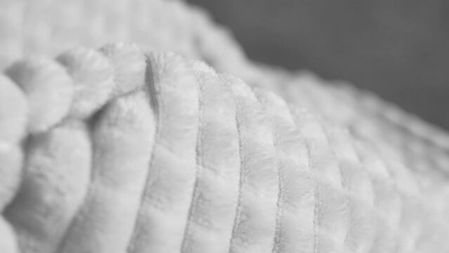 Closeup view 4k stock video footage of fluffy soft textile spinning around slowly. Abstract black and white wavy textured cozy fabric 4k background