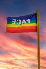 Peace flag waving. The flag in the colors of peace flutters against the backdrop of a dramatically spectacular red sky. Symbol of peace in this time of war. pro concordia labor