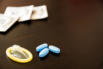 Blue pills to have a long-lasting erection, condom ready and in the background other condoms in...