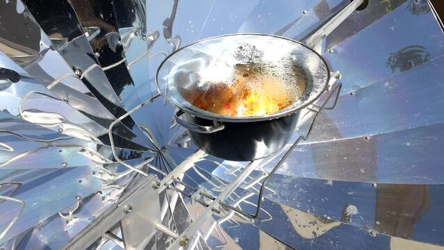Cooking with sun energy, parabolic solar oven in the middle of cooking a dish thanks to solar energy