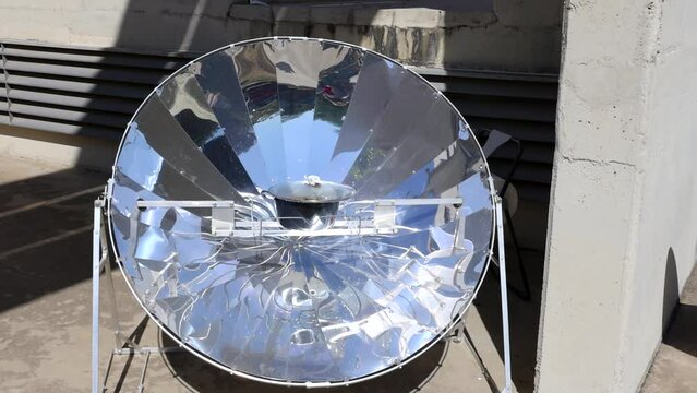 Cooking with sun energy, parabolic solar oven in the middle of cooking a dish thanks to solar energy