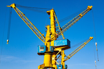 Yellow harbor cranes against the blue sky.