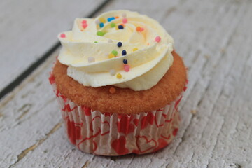 Sweet cake with tutti frutti sprinkles on top on the wooden table white background.