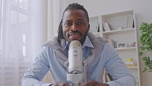 Stylish black man talking on camera, radio host streaming music and news online