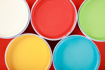 Cans of interior wall paint is placed on a red background.