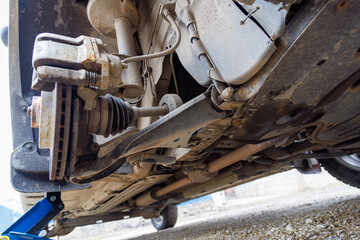 the hub of the front right wheel of a jacked car with a brake disc and pads during a tire change.