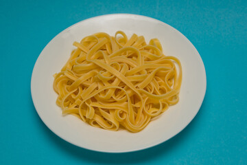 Spaghetti pasta on a white plate on a blue background.