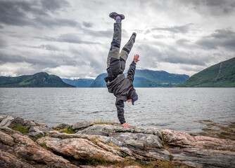 man standing on his hand on the rock