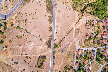 Aerial view of traditional village with rural houses, buildings, highway bridge, countryside roads in Greece. Drone, copter view