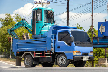 Fototapeta na wymiar A truck loaded with digger ride on a road