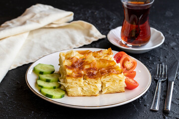 Cheesy pastry. Butter pastry on a dark background. Close-up. local name peynirli su boregi