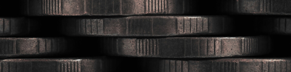 Stacks of coins closeup. Money wall textured banner. Dark brown and gray tinted header made of many coin edges. Economy finance and budget. Bank and loan. Strong macro