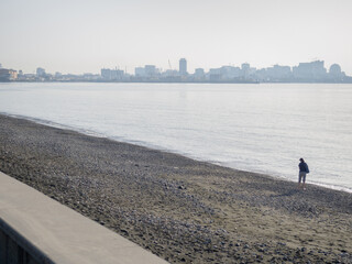 Silhouette of a man on the background of the sea and the city. Loneliness.