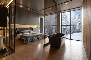 a bedroom and a free-standing bath in a chic expensive interior of a luxurious country house with huge panoramic windows and a magnificent view of the divine forest