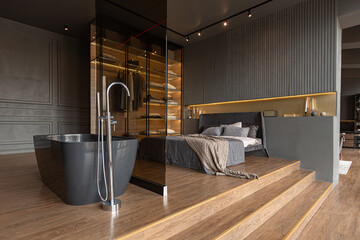 bedroom and freestanding bath behind a glass partition in a chic expensive interior of a luxury...