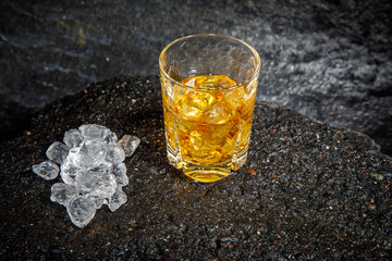 glass of whiskey with ice on asphalt