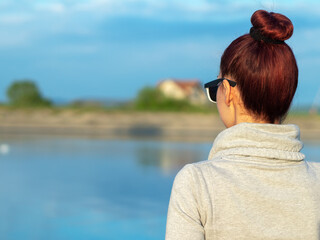 A young woman looking the beauty of the river and nature. Back view. An optimistic look and a relaxing day.