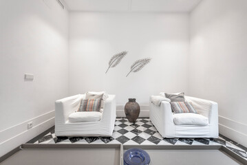 Living room with two individual white fabric sofas with cushions and black and white marble floors
