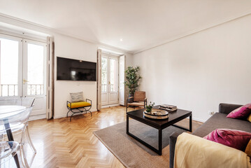 Living room with fabric sofa, dark wood side table, herringbone oak parquet floors and balconies...