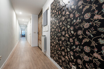 House with a long corridor with a wooden floor and a wall covered with decorative flower paper