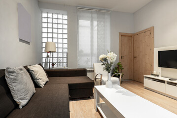 Living room with brown fabric sofa with chaise longue, white sideboard with flat tv, skylight wall...