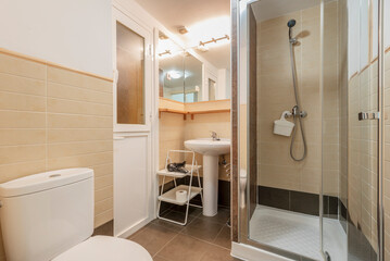 Fototapeta na wymiar Bathroom with matching pedestal white porcelain sink, frameless mirrors and glass door shower stall