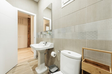 Bathroom with white porcelain sink on pedestal of the same material, rectangular frameless mirror, light tile border