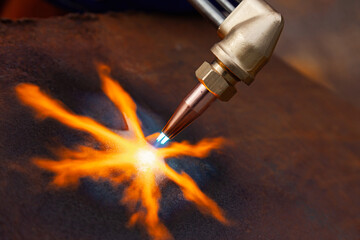 Gas cutting of metal. Gas cutter with copper nozzle with a stream of fire directed at the metal....