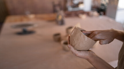 DIY work close-up of a creative woman sculpting a bowl from raw clay in a pottery workshop during a master class or workshop. The concept of craft and craftswoman.