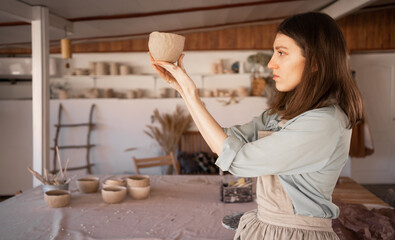 . woman artist sculpts from wet clay in studio. ceramist makes handicrafts from ceramics. female industriousness concept.